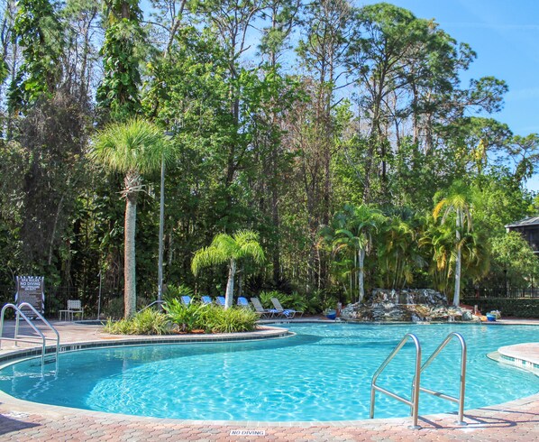 Una piscina al aire libre, sillones reclinables de piscina