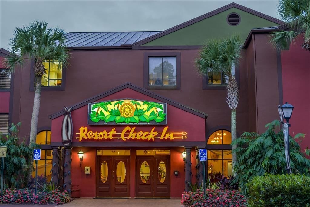 A building with a sign reading 'Resort Check In' and a palm tree in front.