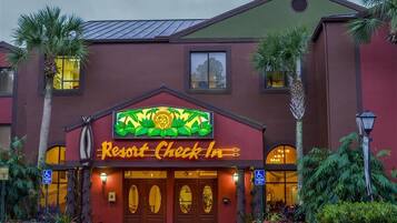 A building with a sign reading 'Resort Check In' and a palm tree in front.