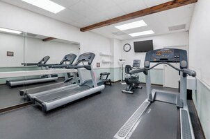 Una palestra con tapis roulant, una cyclette e una panca per pesi.