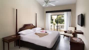 A hotel room with a bed, bedside tables, a chair, a TV, and a balcony with a view.