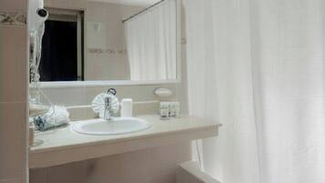 A bathroom with a toilet, sink, mirror, and shower curtain.