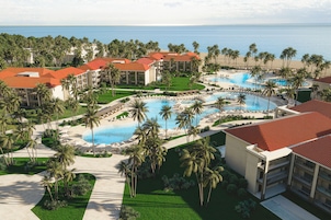 A resort with multiple swimming pools, palm trees, and beachfront views.