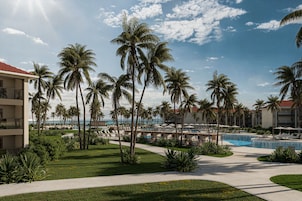 A resort with a pool, palm trees, and a clear sky.