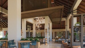 Un hall amplio con techos altos, mobiliario moderno y elementos decorativos como lámparas colgantes y una columna central con piedras apiladas.