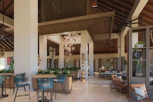 A spacious lobby with high ceilings, modern furniture, and decorative elements like hanging lights and a central column with stacked stones.
