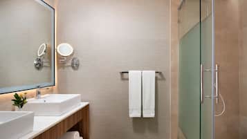 Une salle de bain moderne dotée d’un grand miroir, de deux vasques, d’une douche à parois de verre et d’un porte-serviettes.