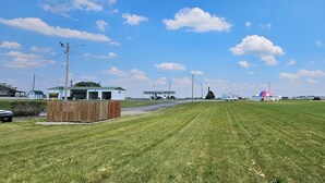 A grassy field with a small building, a fenced area, and a few vehicles. - Briarwood Inn of Sparta (Sparta)