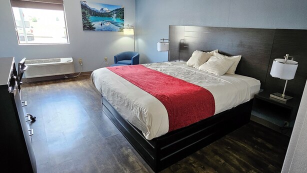 A modern bedroom with a large bed, a desk with a computer, a chair, and a window with a view of a lake. - Briarwood Inn of Sparta (Sparta)