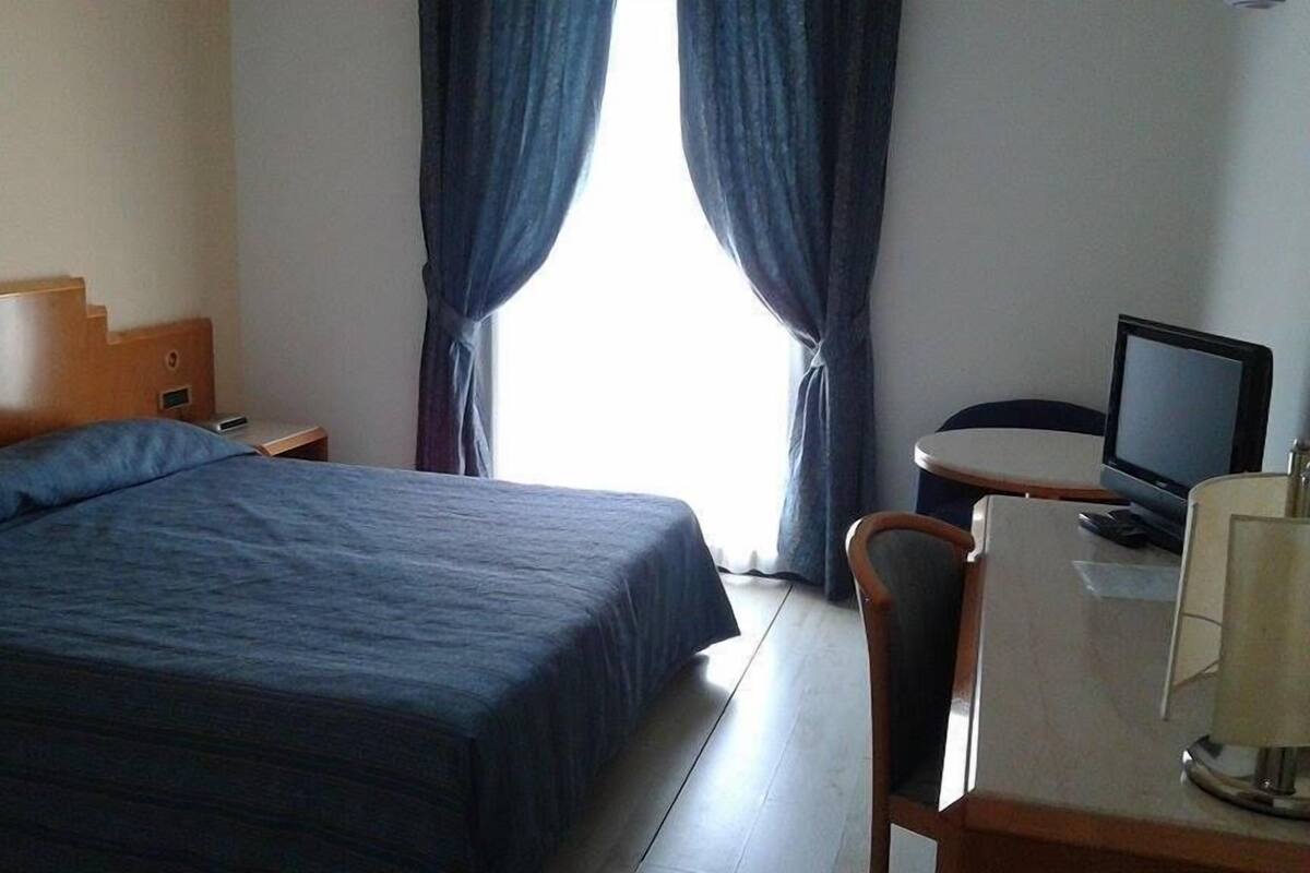 A hotel room with a bed, a desk with a computer, and a television.