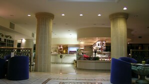 Um hall amplo com tetos altos, colunas grandes e um espaço de bar central.