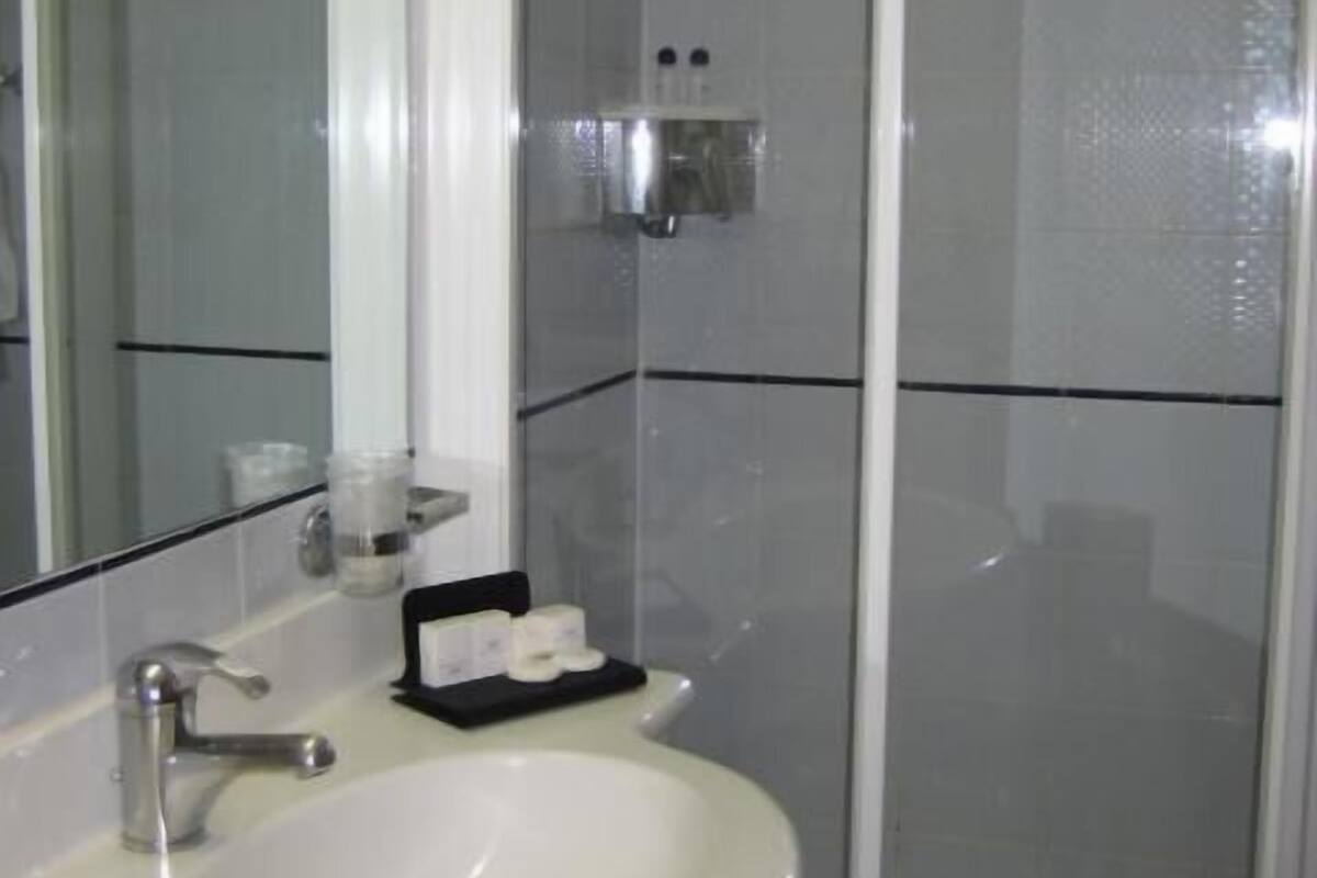 A bathroom with a white sink, a mirror, and a glass shower enclosure.