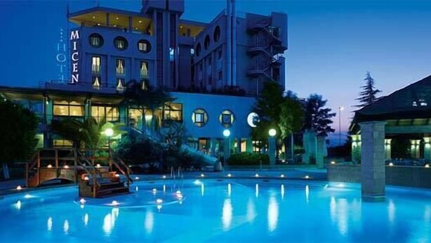 Um hotel com piscina, fachada bem iluminada e design arquitetônico moderno.