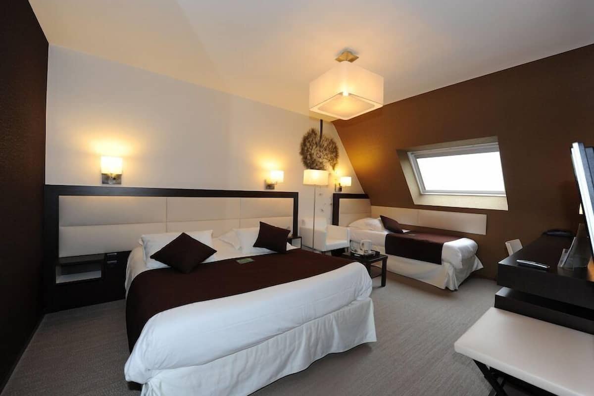 A hotel room with a large bed, a sofa, a desk, and a window.