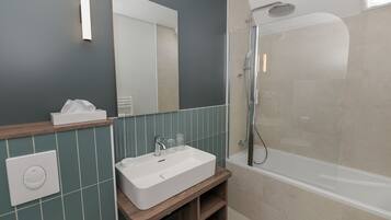 Une salle de bain avec un lavabo blanc, un miroir, une douche et un porte-serviettes.