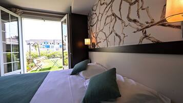 Camera d'albergo con un letto, vista all'esterno e una parete decorata con un motivo a ramo.