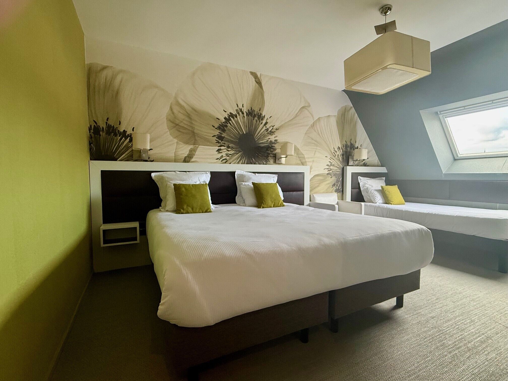 Une chambre à coucher moderne avec un grand lit, deux tables de chevet et un banc intégré.