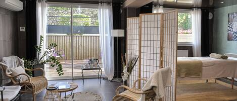 A modern hotel room with a balcony, wicker furniture, a bed, and a view of the outdoors.