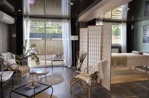 Habitación de hotel moderna con balcón, mobiliario de mimbre, una cama y vistas al exterior.