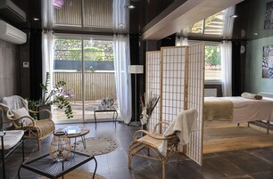 A modern hotel room with a balcony, wicker furniture, a bed, and a view of the outdoors.