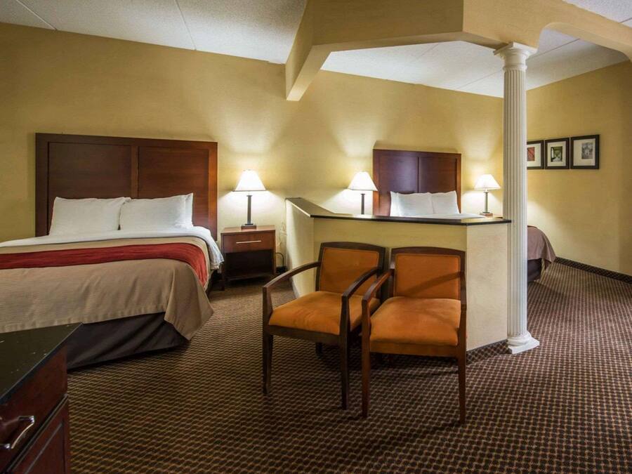 Ein Hotelzimmer mit einem Bett, zwei Nachttischen mit Lampen, einem Schreibtisch und einem Stuhl sowie einer großen Säule.