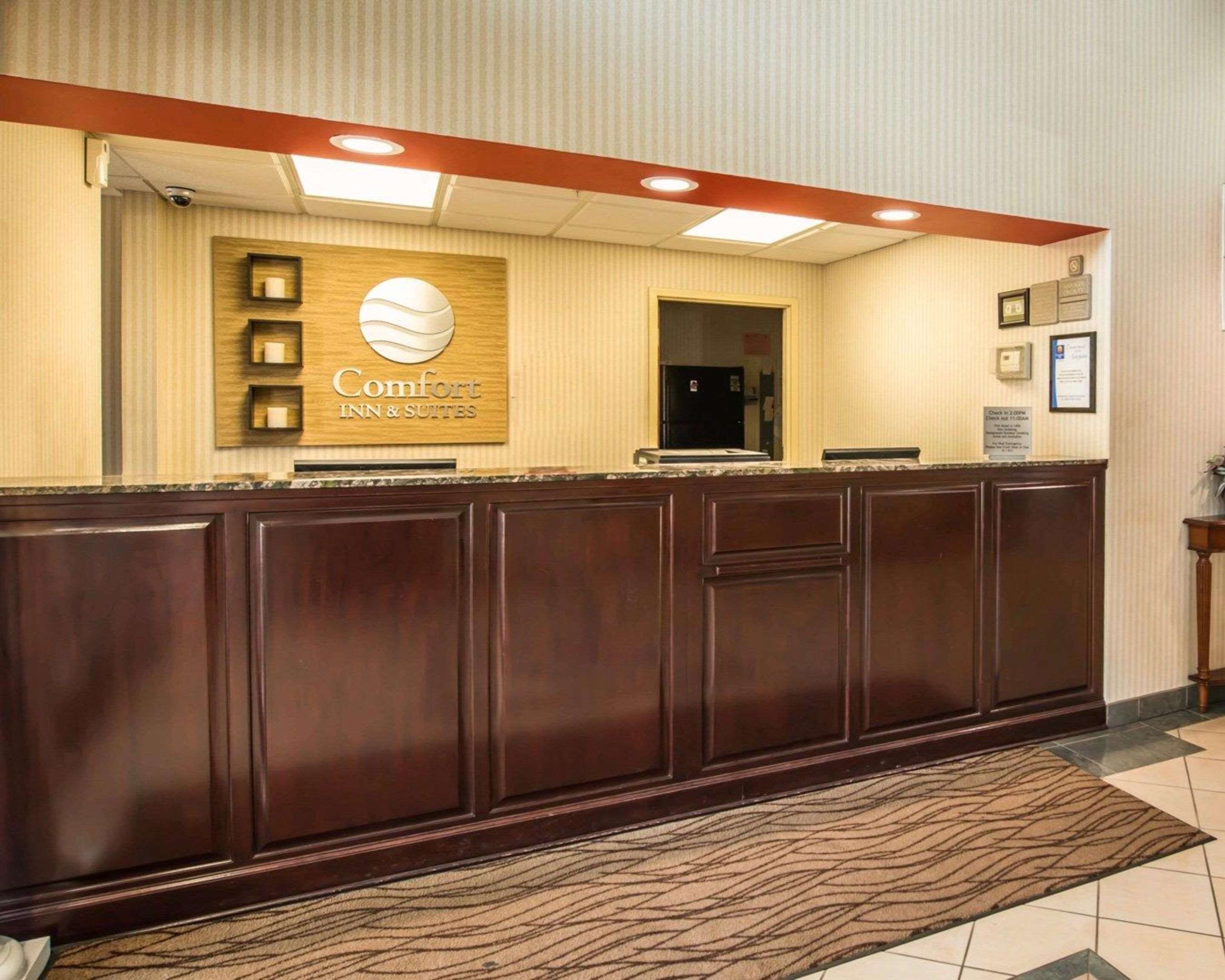 A reception desk with a sign for Comfort Inn & Suites, a security camera, and a framed certificate on the wall.