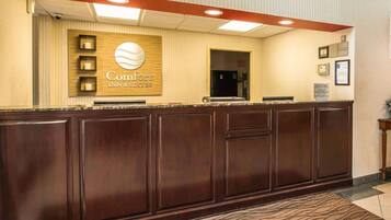 A reception desk with a sign for Comfort Inn & Suites, a security camera, and a framed certificate on the wall.