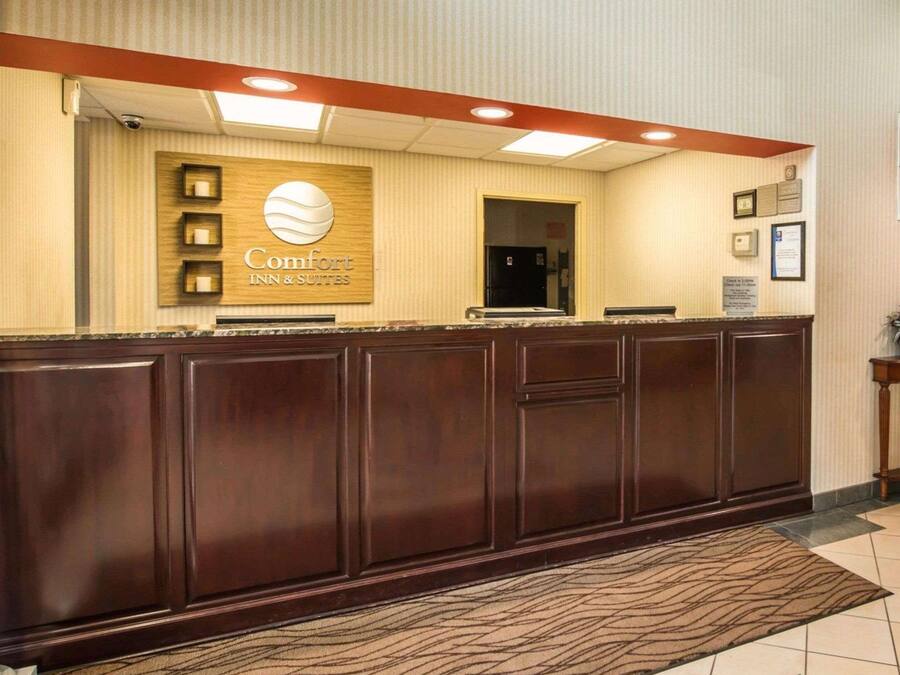A reception desk with a sign for Comfort Inn & Suites, a security camera, and a framed certificate on the wall.