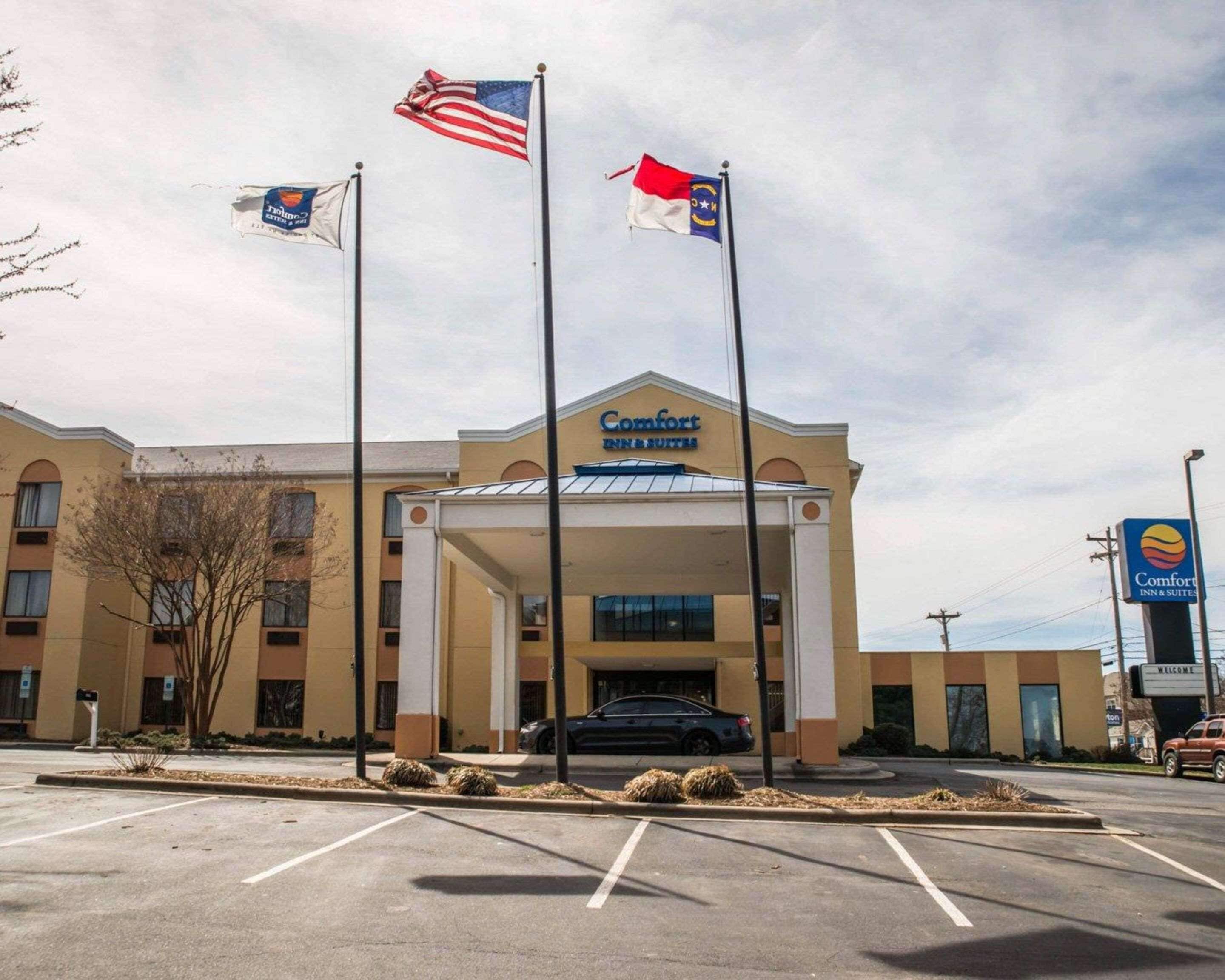 Un hôtel Comfort Inn & Suites doté d’un parking, de plusieurs drapeaux et offrant une vue sur un ciel dégagé.
