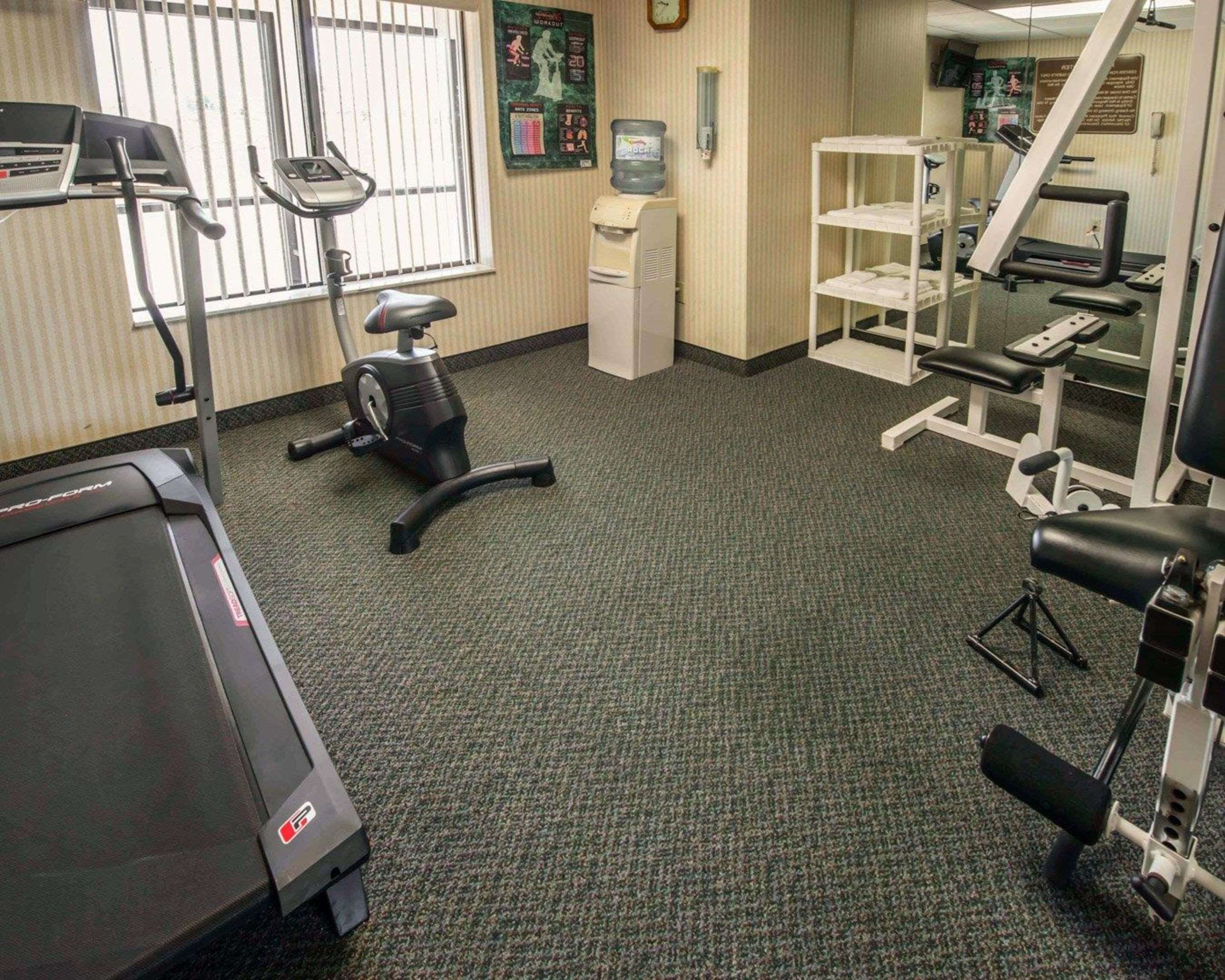 A gym with cardio equipment, a treadmill, an elliptical, and free weights.