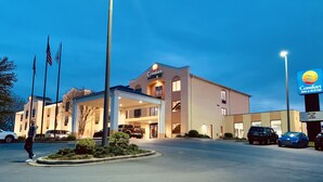 Um hotel Comfort Inn & Suites com entrada coberta, várias bandeiras e um estacionamento com carros.