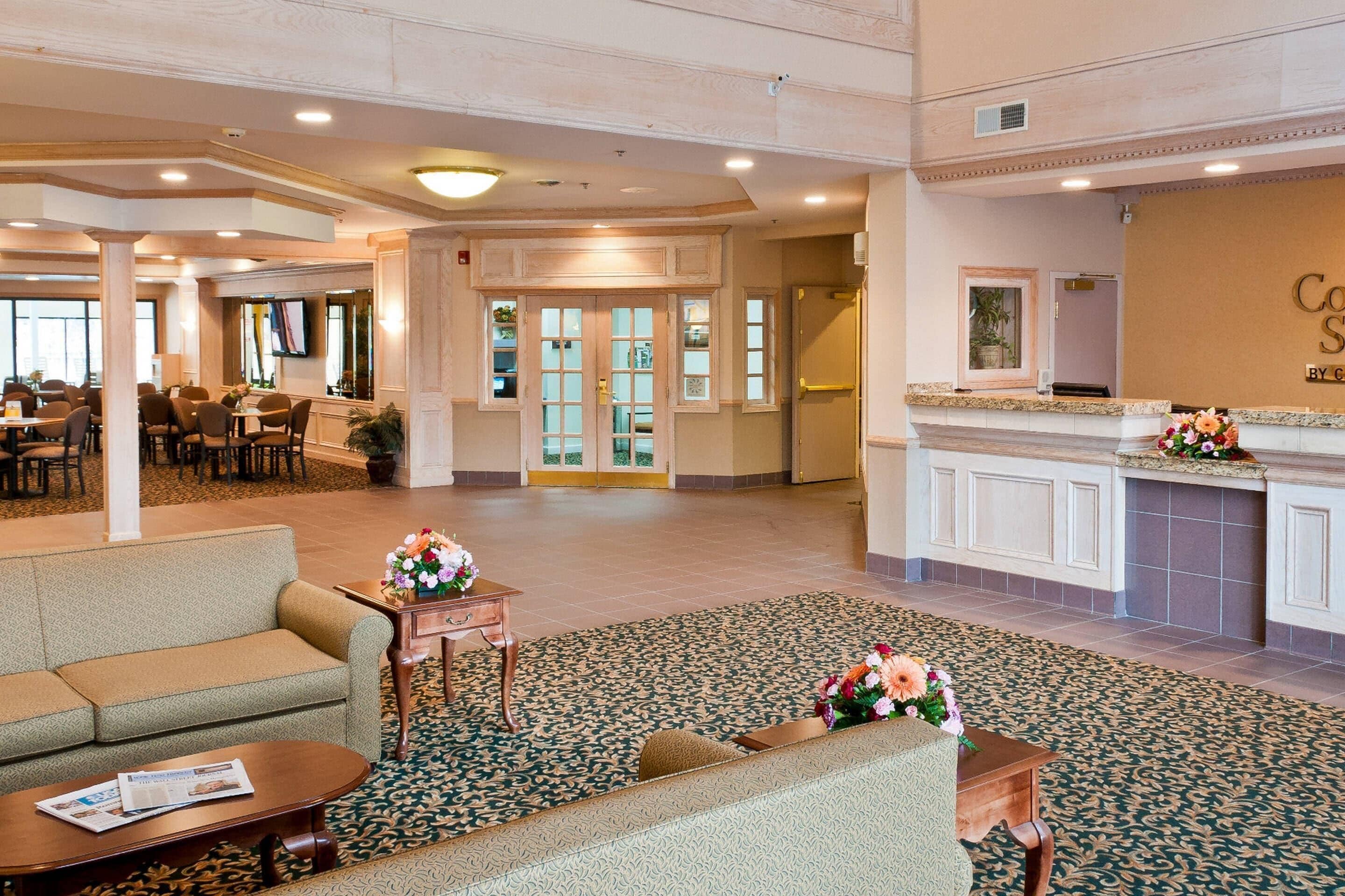 A hotel lobby with a reception desk, seating area, and a television screen.