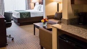 A hotel room with a bed, a sofa, a coffee maker, and a TV.