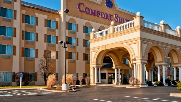 A hotel with a large arched entrance, multiple balconies, and a prominent sign reading "Comfort Suites".