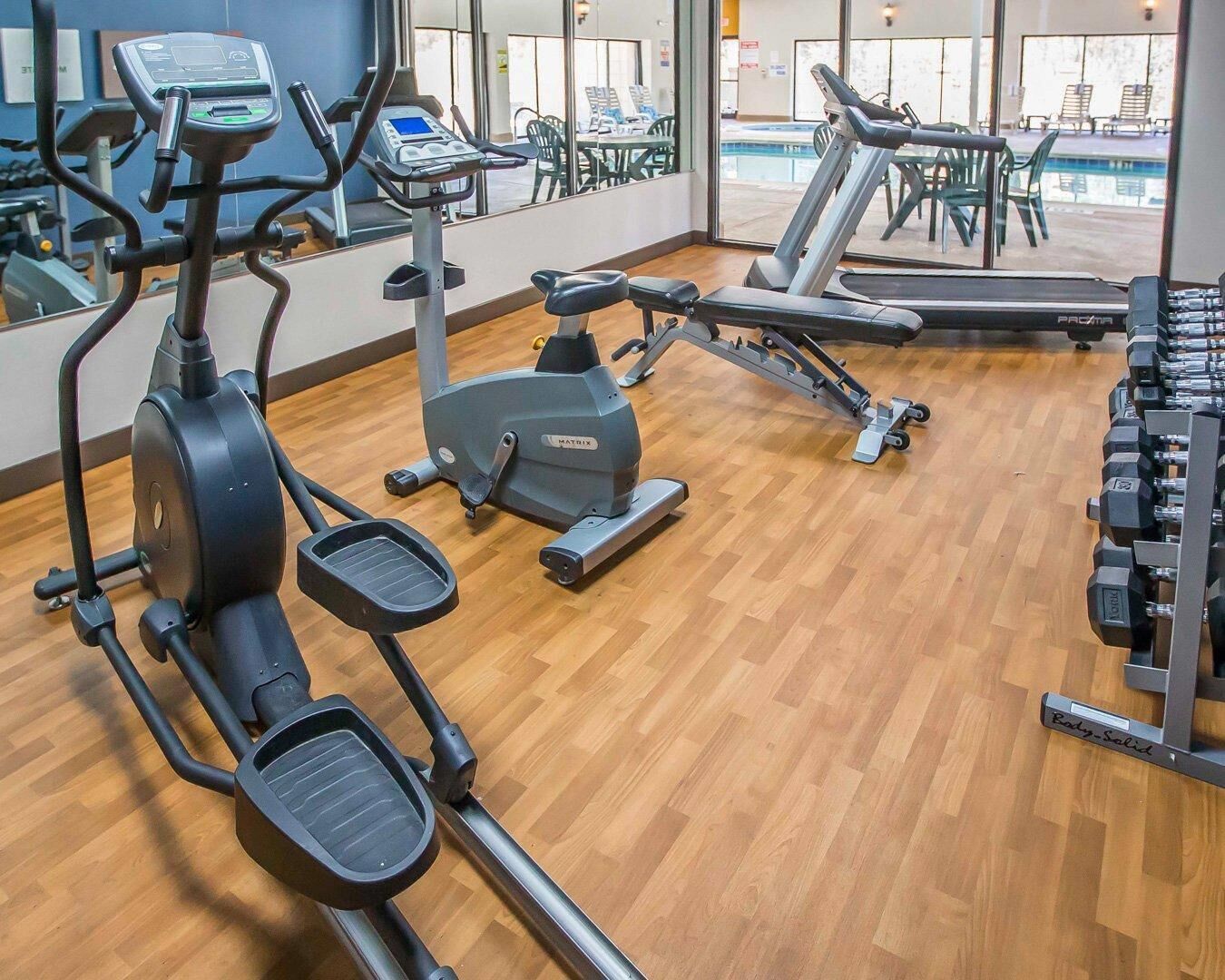 Un gimnasio con cintas de correr, elípticas y bancos para pesas.