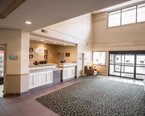 A hotel reception area with a counter, a seating area, and a large window. - Comfort Suites University Area Notre Dame - South Bend (South Bend)