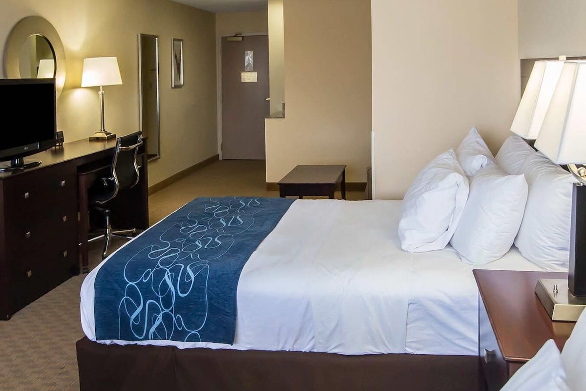 A hotel room with two beds, a desk with a computer, a TV, and a lamp.