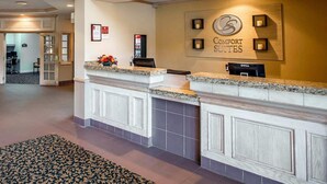 A hotel reception area with a marble counter, a Dell computer, and a sign for Comfort Suites.