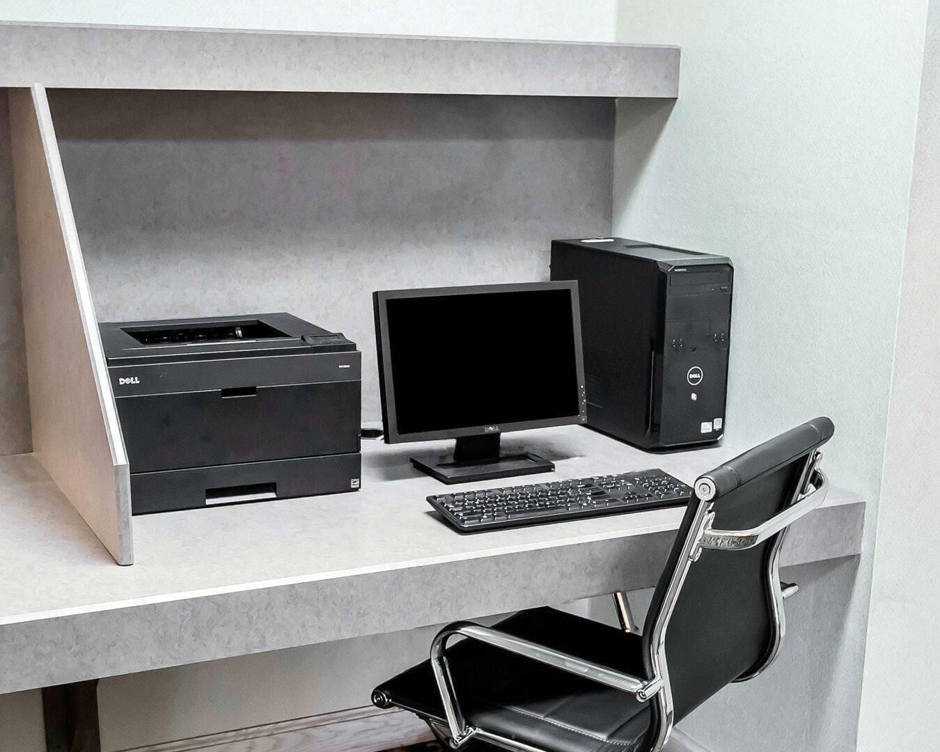 Un escritorio moderno con una computadora de escritorio, monitor, teclado e impresora.