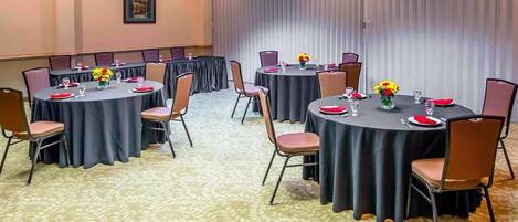 A conference room with round tables, chairs, and floral centerpieces.