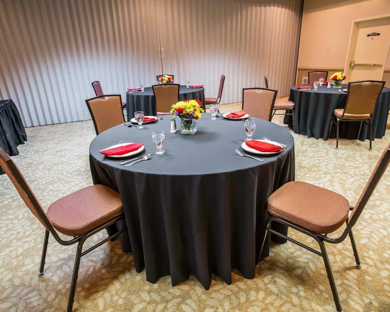 A conference room with a round table, chairs, and a carpeted floor.