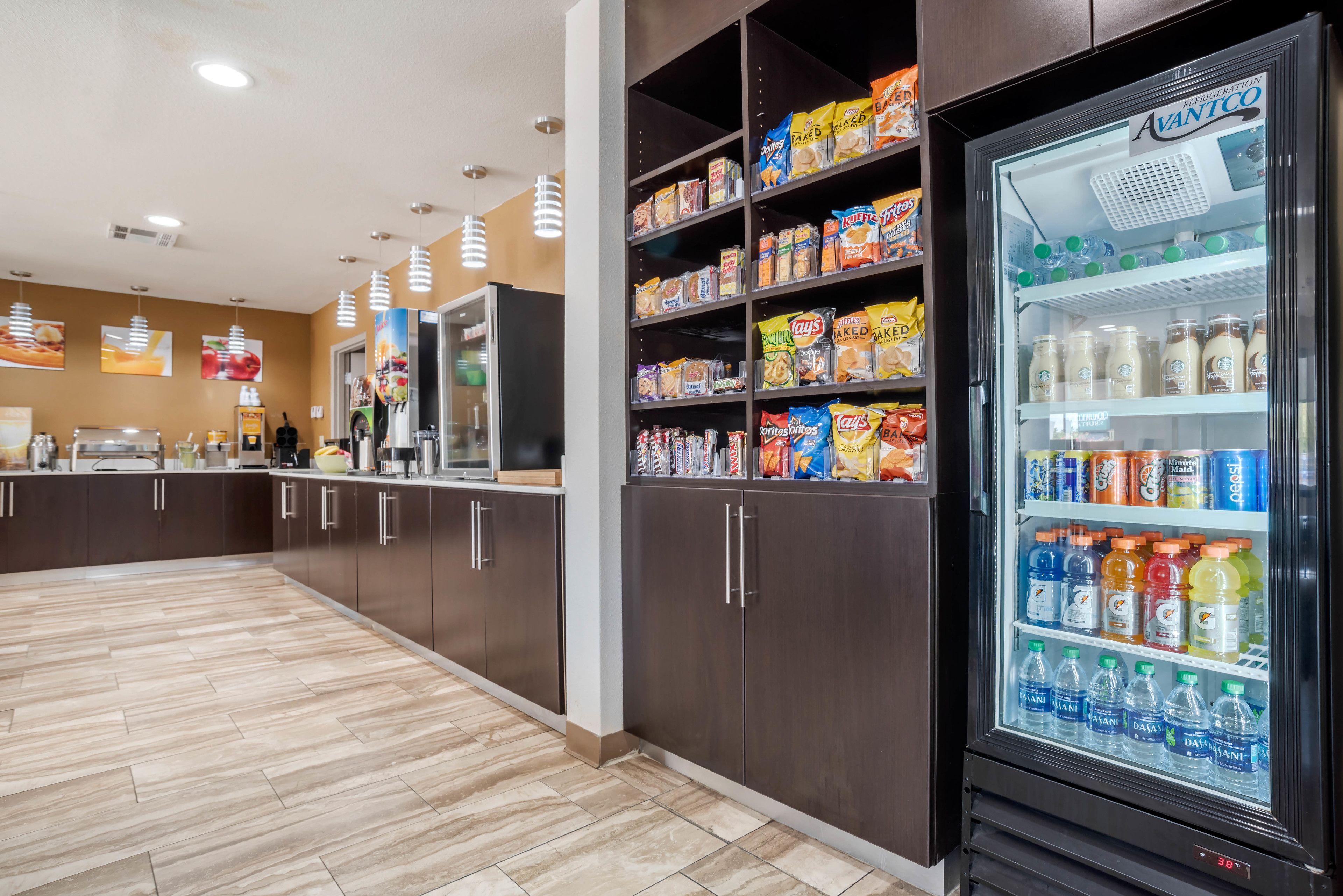A clean, modern kitchen area with a refrigerator stocked with beverages and snacks.