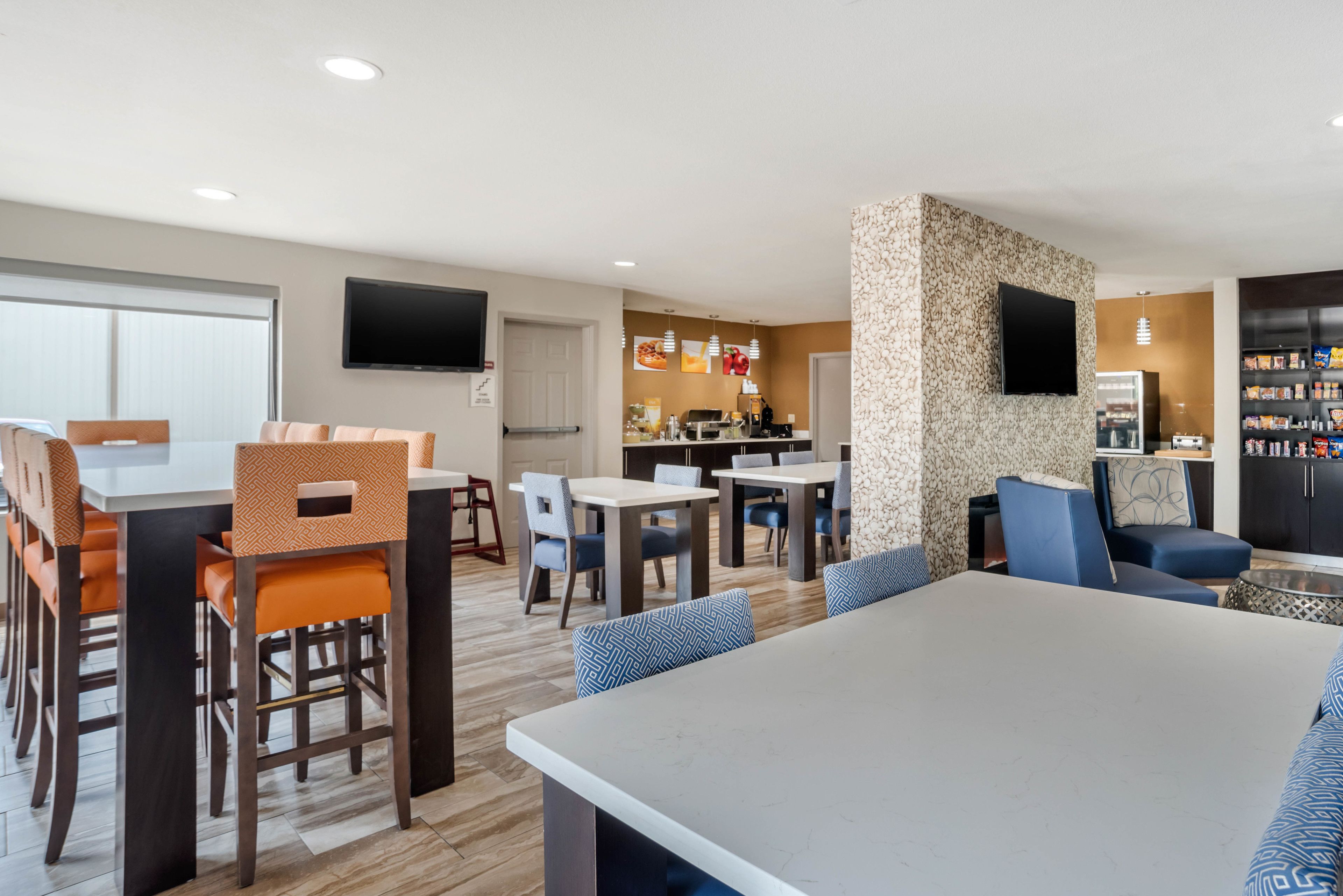 A modern hotel lobby with a dining area, kitchen, and a bar.