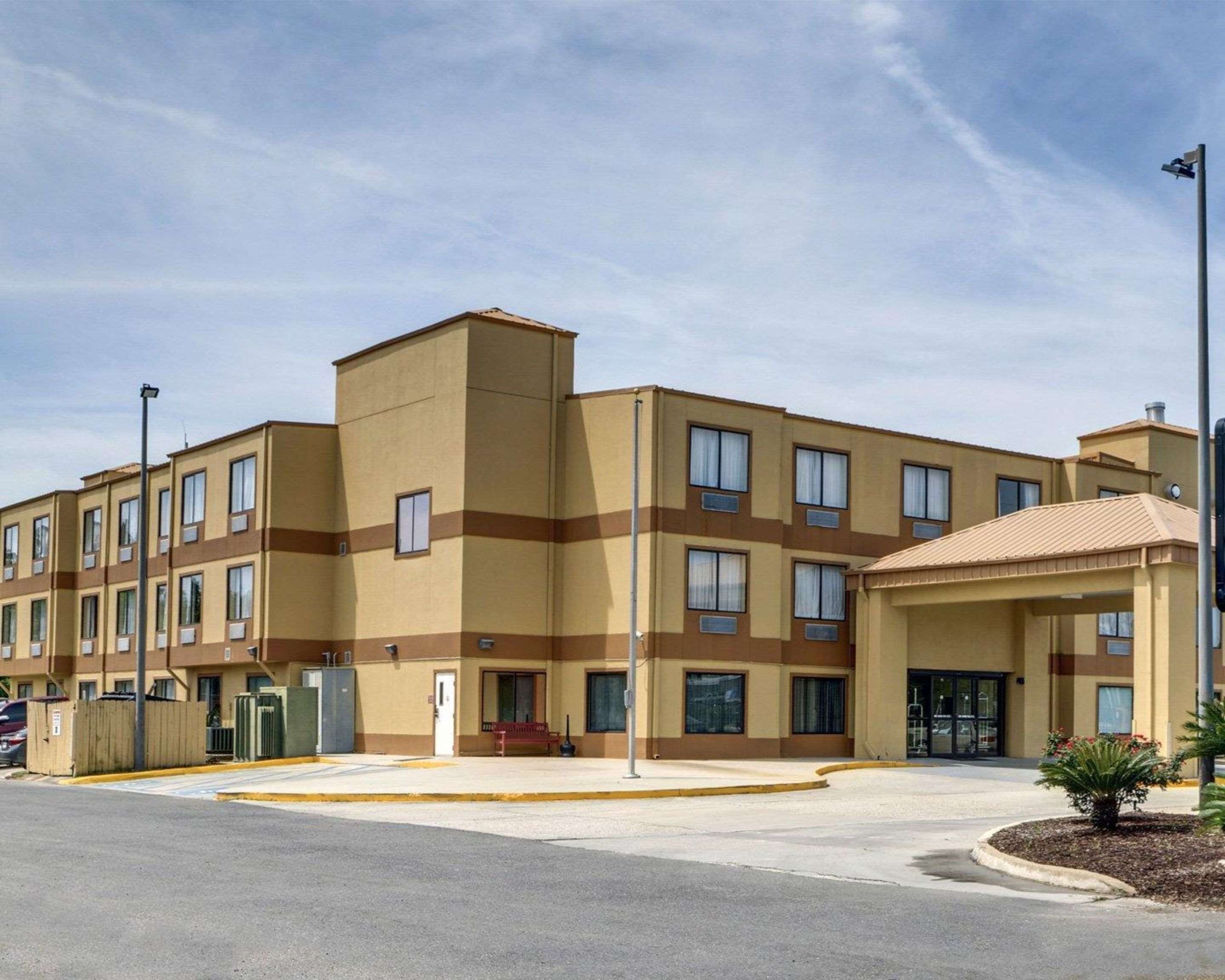 A multi-story hotel with a flat roof, multiple windows, and a covered entrance.