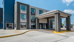 A modern building with a covered entrance and a clear sky. - Quality Suites Baton Rouge East - Denham Springs (Baton Rouge)