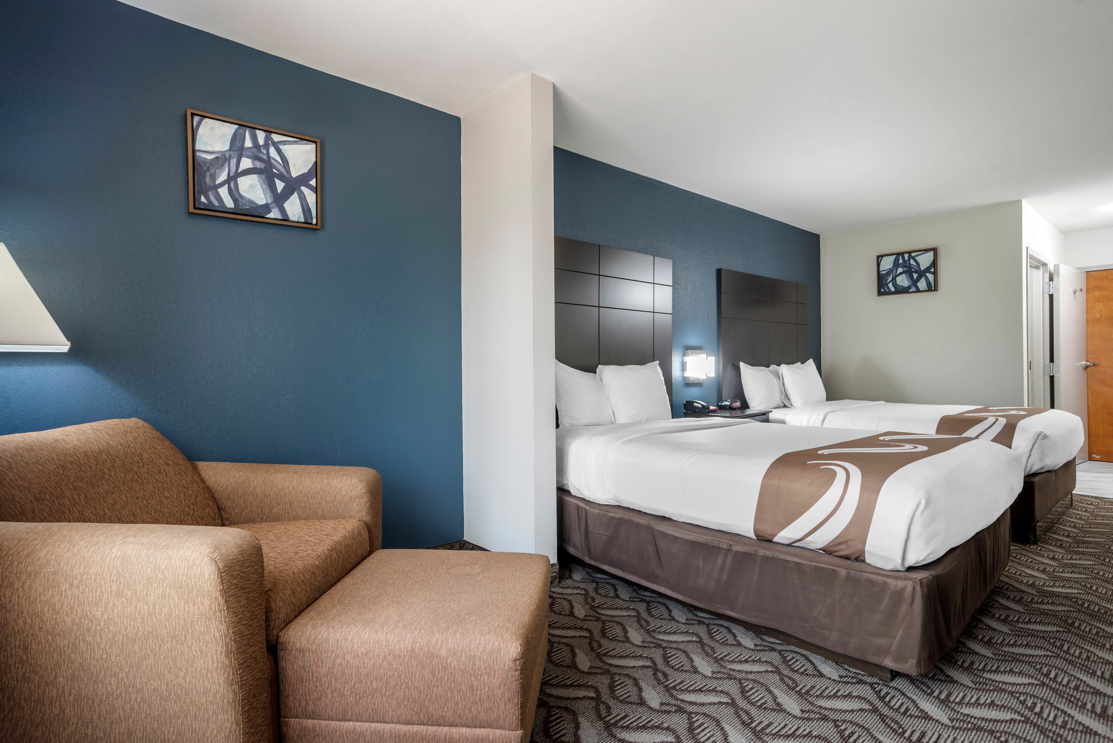 Ein Hotelzimmer mit zwei Betten, einem Sofa und einem großen abstrakten Gemälde an der Wand.