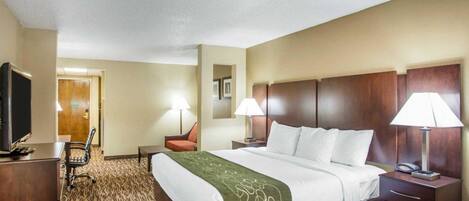 Habitación de hotel con una cama grande, dos mesitas de noche con lámparas, televisión, escritorio y una silla.