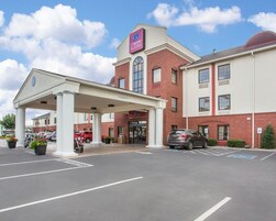 Un hotel Comfort Suites con entrada cubierta, aparcamiento y cielo despejado.