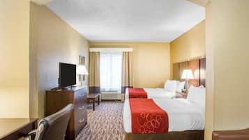 A hotel room with a bed, a desk with a TV, a chair, and a window with curtains.