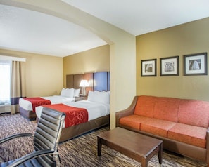 A hotel room with two beds, a sofa, a chair, a coffee table, and framed pictures on the wall. - Comfort Suites Lebanon (Lebanon)
